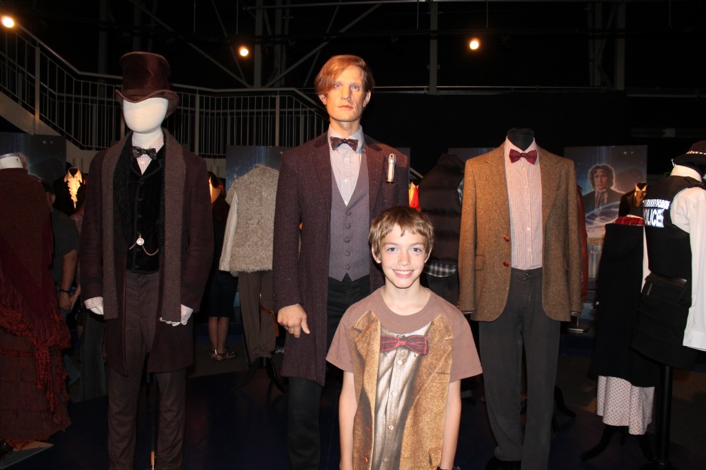 The author's son wearing a Doctor Who "costume" shirt standing in front of a wax statue of Matt Smith