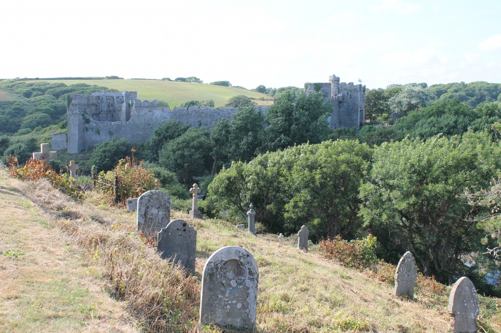 Very old weathered gravestones overlooking a medieval castle and rolling green hills