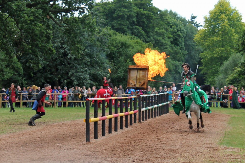 A costumed rider sets fire to a target bag with his flaming lance