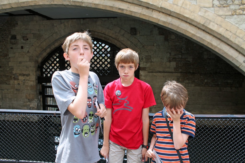 Photo of three kids making sad/scared faces in front of a castle drawbridge.