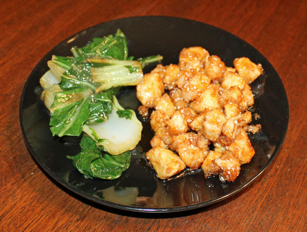 sesame chicken plated with a side of bok choy