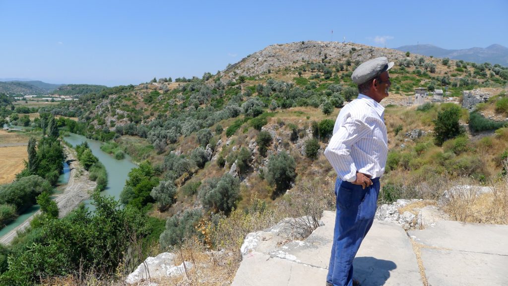 A local guide with a large mustache stands looking off a cliff