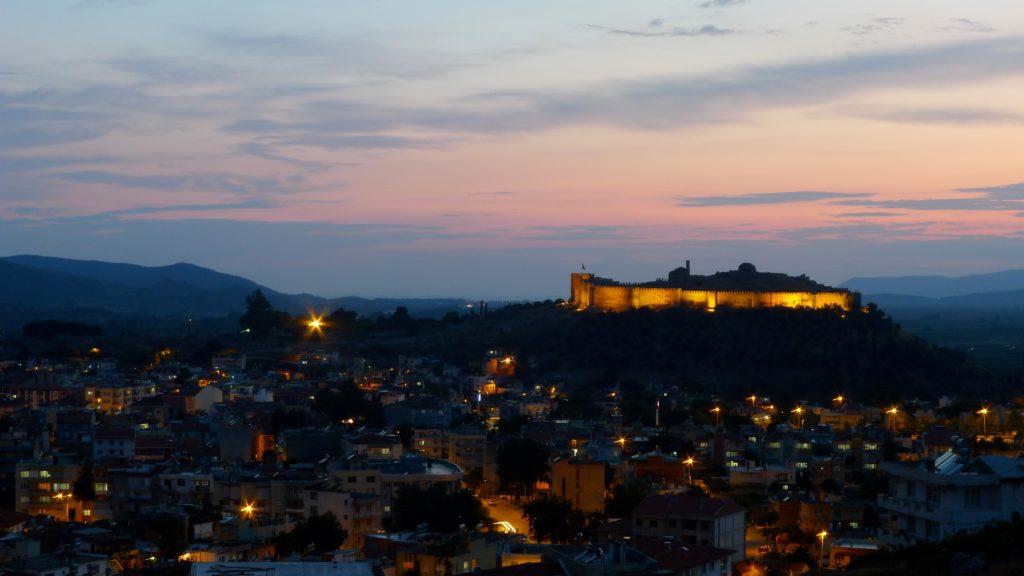 A castle on a hill overlooking a city at twilight