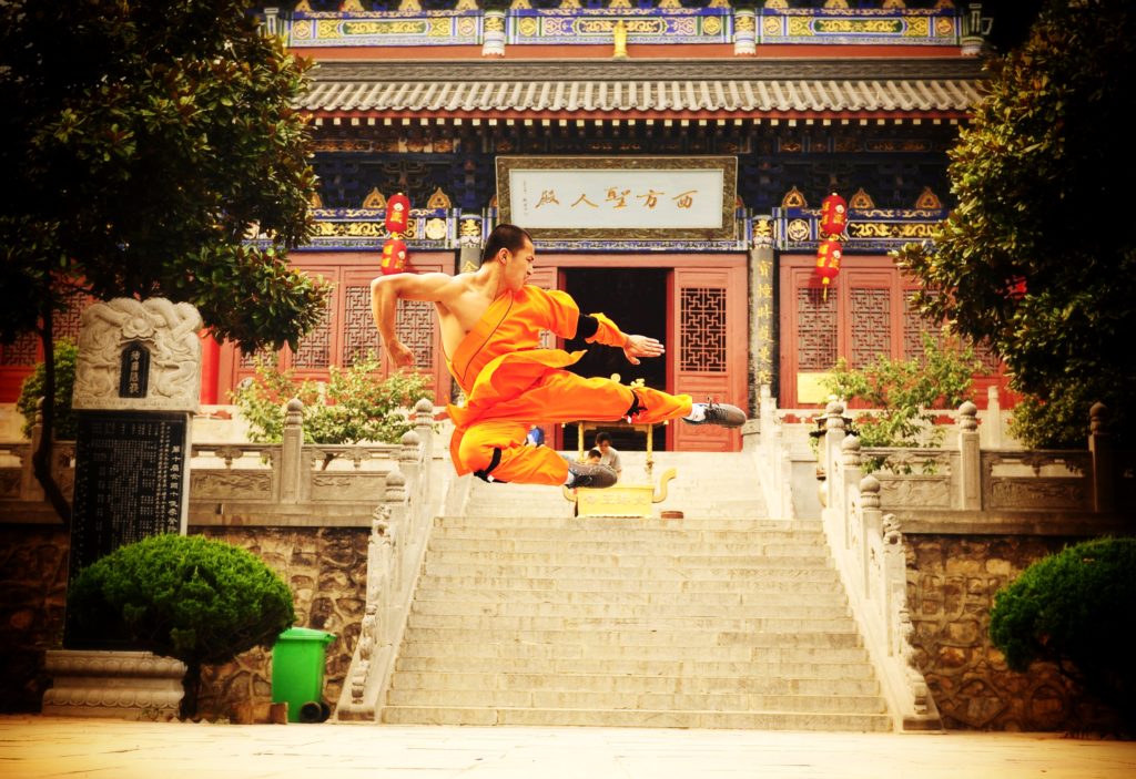 A shaolin monk is pictured flying through the air in an impressive wushu form.