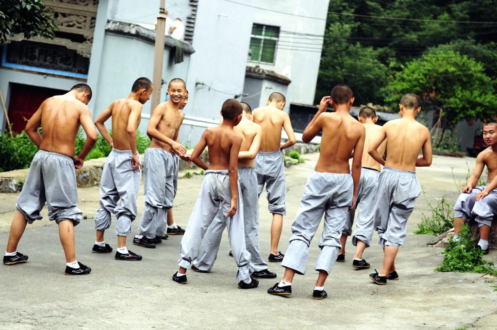A group of teenage boys in grey pants laugh together