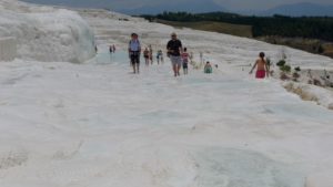 Tourists climb a surreal, pure white hill